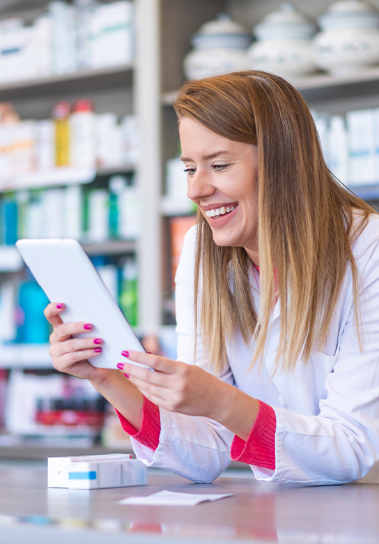 Frau nutzt Smartphone in der Apotheke - lachend