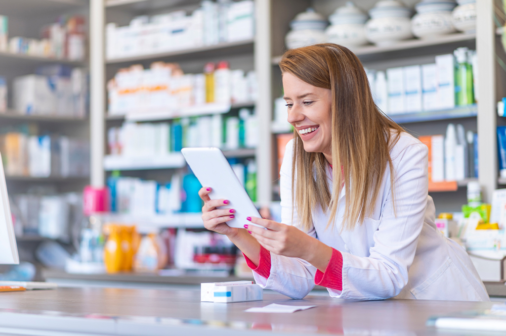 Frau nutzt Smartphone in der Apotheke - lachend