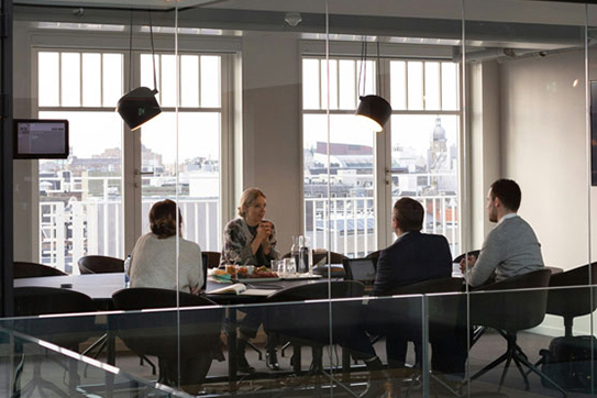 Meetingraum mit Personen am Tisch im Konferenzraum mit Glaswänden
