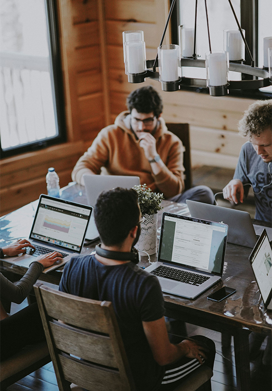 Team arbeitet gemeinsam an Laptops im Büro
